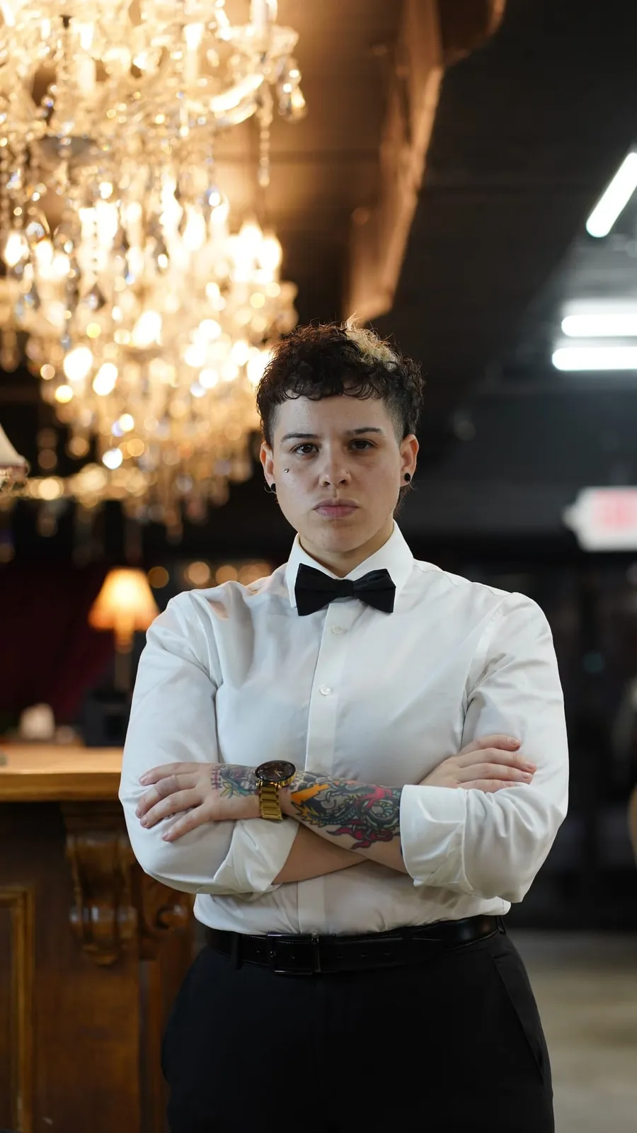 Barber in a white shirt and bow tie standing under a crystal chandelier