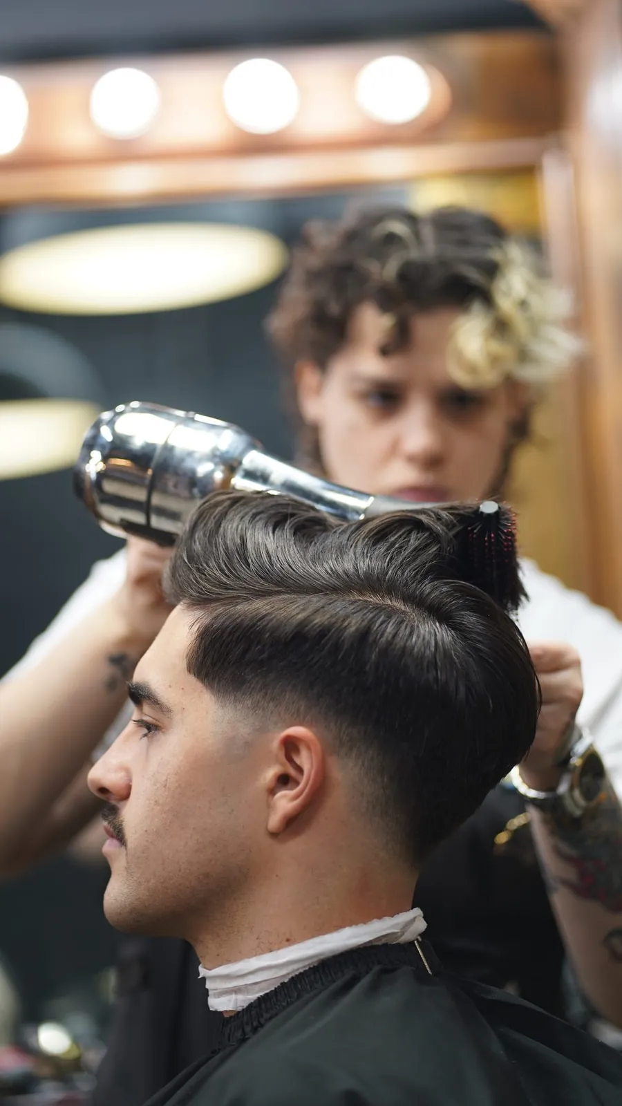 Barber blow-drying a client's pompadour with a round brush