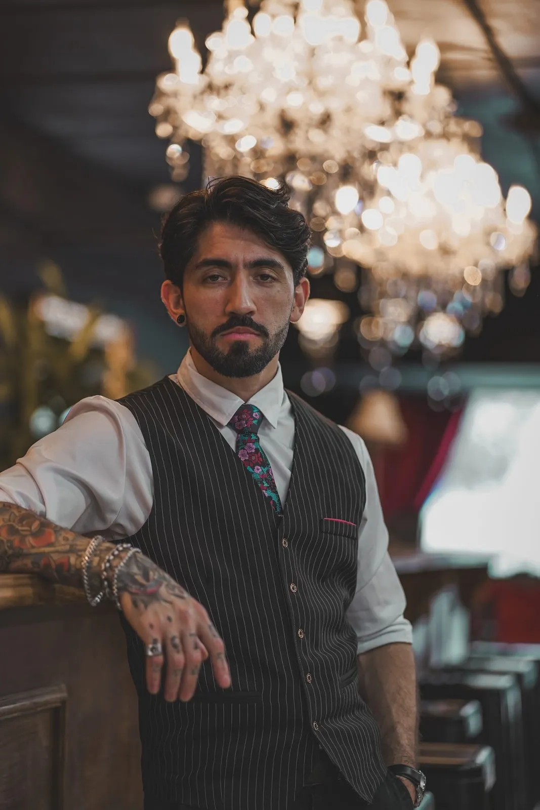 Barber in a pinstripe vest and floral tie at the shop counter