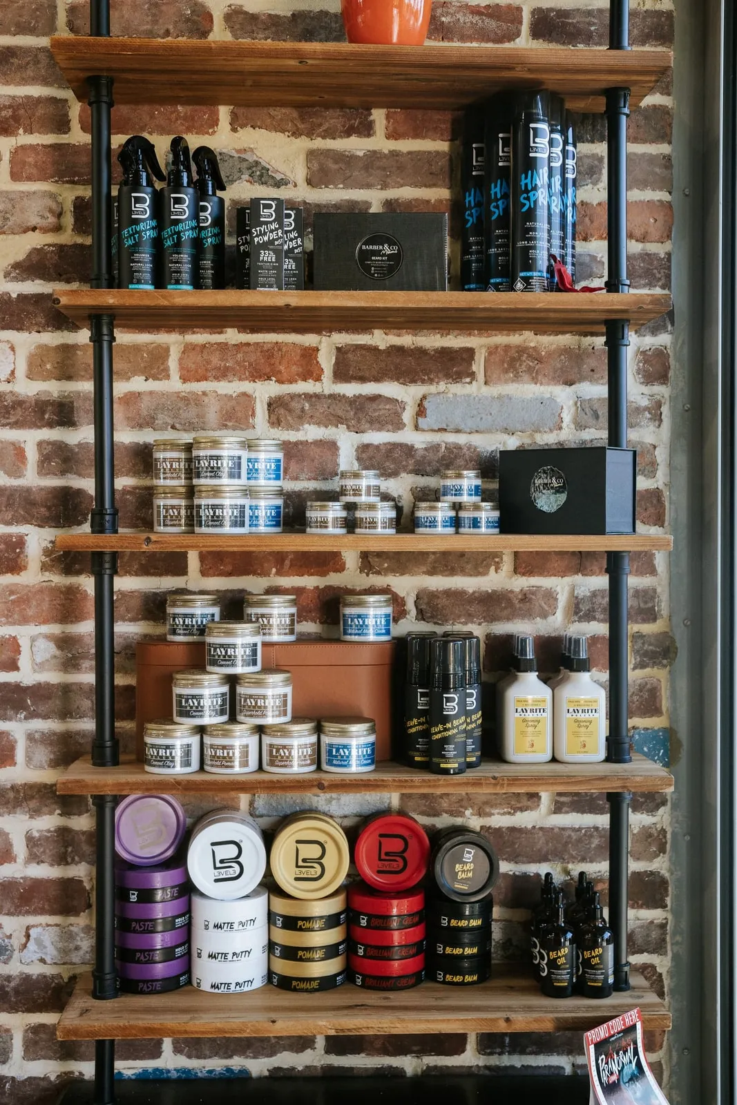 Shelves of pomade, beard balm, and hair spray against a brick wall