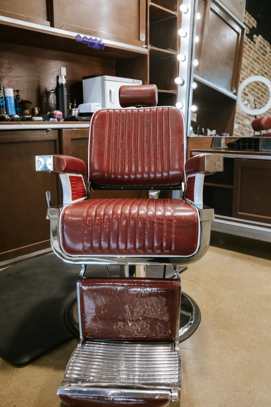 Burgundy vintage barber chair in front of a lighted mirror