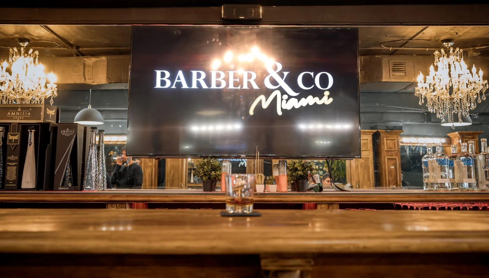 Barber & Co Miami logo on a screen above the shop bar