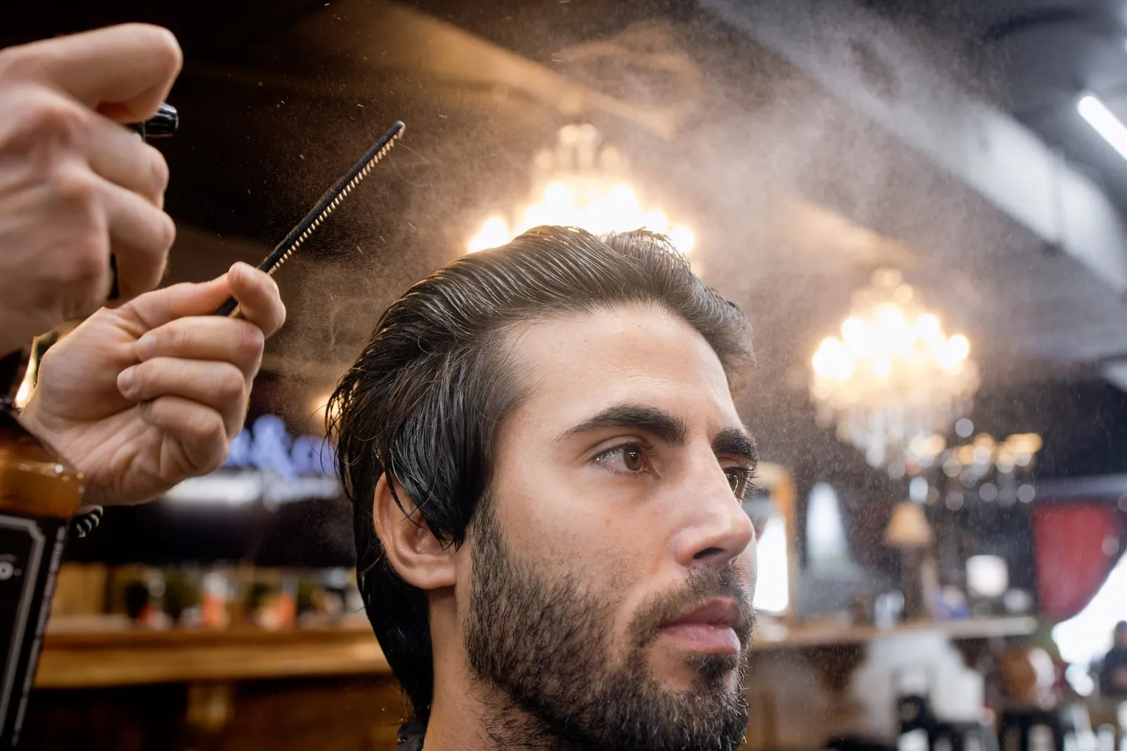 Barber spraying and combing a client's slicked hair