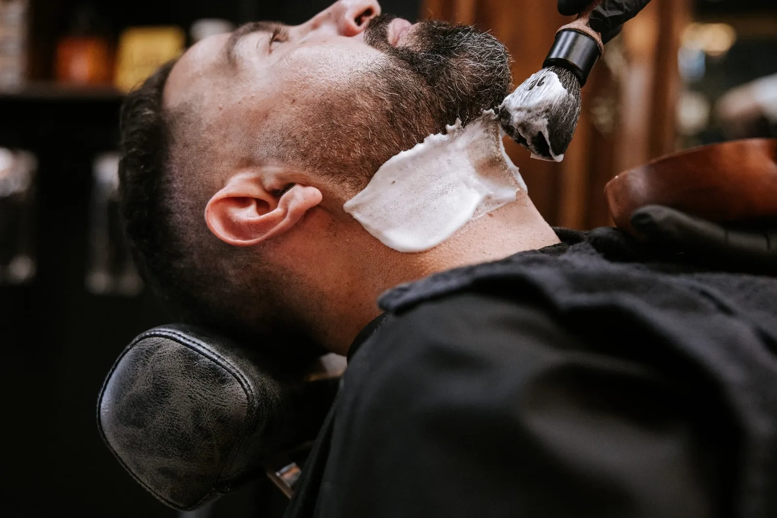 Shaving brush lathering a client's neck before a beard shave