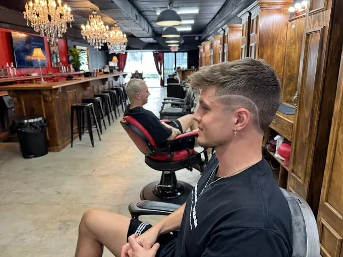 Client with a hard-part fade seated beside the shop bar