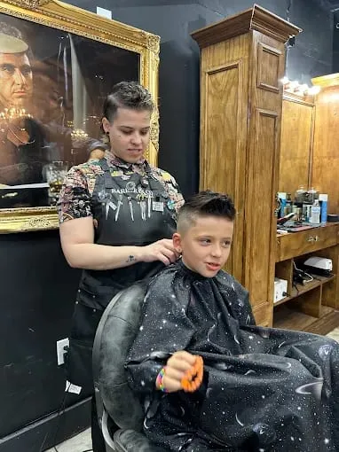 Barber cutting a boy's hair while he wears a star-pattern cape