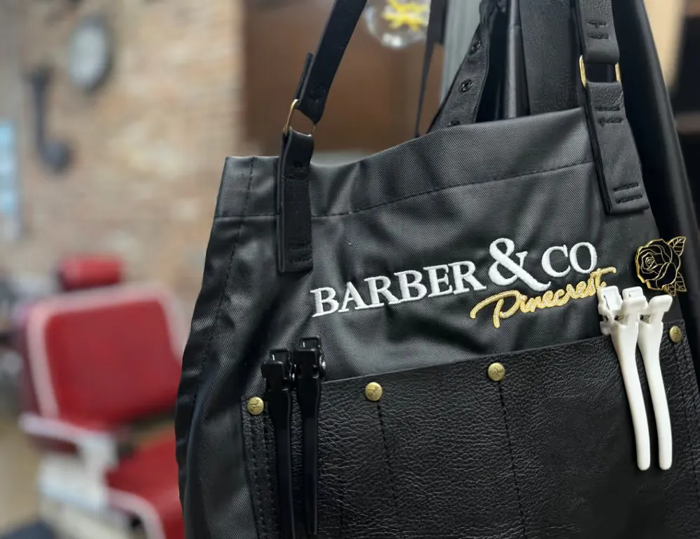 Closeup of a barber apron with the words 'Barber & Co Pinecrest' in the center.